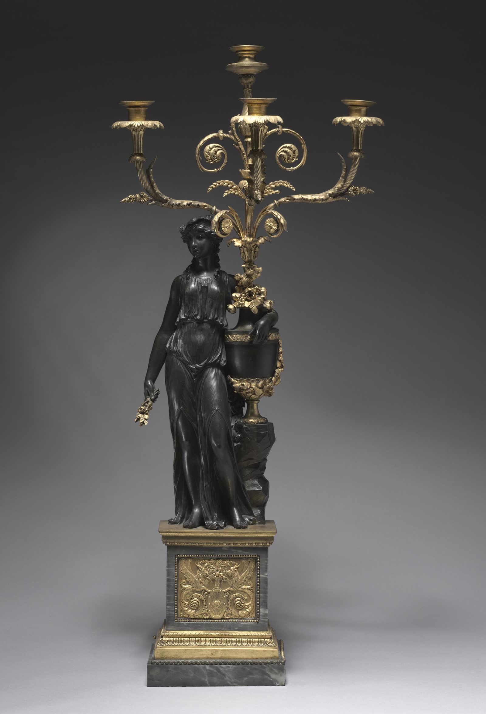 Candelabro de bronze escuro e dourado com figura feminina